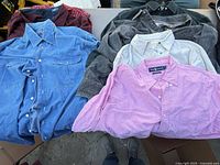 Seven shirts laid out on table showing variety of colors and fabrics
