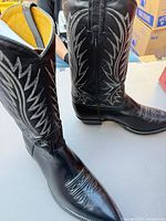 Full view of both black leather cowboy boots showing decorative stitching and overall condition
