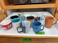 Full lot of thirteen assorted mugs on shelf