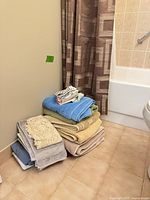 Stack of assorted towels, washcloths and hanging geometric shower curtain