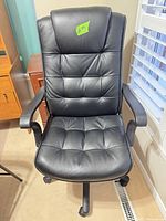 Front view of black padded office chair showing seat, backrest and armrests