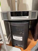 Bose silver media center atop black bass module