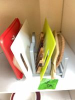 Rack holding assorted cutting boards red, white, wooden striped, lime green, round, paddle