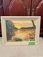Full view of framed sunset landscape painting with cream frame