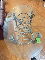 Oval glass coffee table showing metal scroll base and glass top