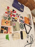 All items arranged on bed including clock radio, boxed games, darts, books, accessories