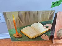 Still life painting with candle and open book on green surface
