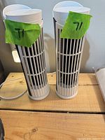 Front view of two white USB tower fans standing side by side on wooden surface