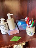 two pump dispensers, storage tub, pencil holder with pens, pill organizer partially visible