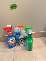 Group shot of four visible cleaner bottles on tile floor