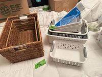 woven nesting baskets and stack of plastic organizers on bed
