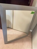 Full view of square mirror leaning against wall