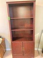 Full view of tall dark veneer bookcase showing three open shelves and lower two-door cabinet