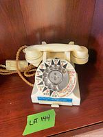 Front view of cream rotary telephone on shelf