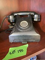Front view of black rotary telephone on shelf