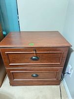 front view of two-drawer wooden filing cabinet showing handles and overall finish