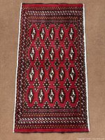 Full view of red Turkoman rug with geometric pattern and fringe