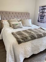 Full view of made king bed with headboard, bedding and throw blanket