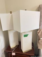 Two cream ceramic table lamps with square shades on nightstand