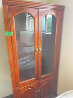 Front view of wood curio cabinet with glass doors closed