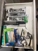 Drawer view showing full contents: flatware, knives, shears, measuring cup, organizer
