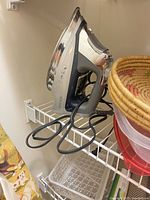 Close-up of Black+Decker iron on shelf with white tray and wicker basket