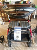 Front view of red Evolution Trillium walker showing seat, backrest, storage pouch and wheels