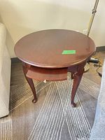 Full view of round wooden side table showing drawer and legs