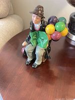 Full view of figurine showing seated man with balloons