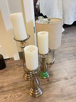 Three metallic candlesticks with candles and glass table lamp