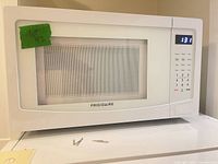 Front view of white Frigidaire microwave showing control panel and door window