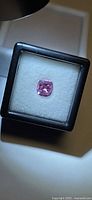 Bright pink cushion cut spinel in display box, top view