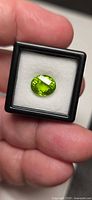 Front view of oval vivid green peridot in display box