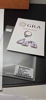 Ring atop GRA moissanite report and case