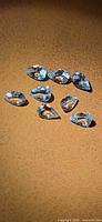 Eight pear-cut light blue aquamarine gemstones on tan background