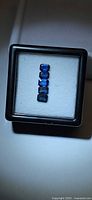 Five emerald-cut blue sapphires in display box