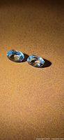 Two oval faceted blue aquamarines on display surface
