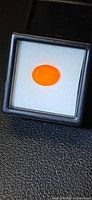 Loose oval orange fire opal in display case