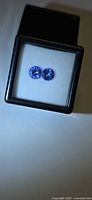 Pair of round violet-blue gemstones in clear-top display box