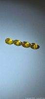 Four oval yellow sapphires under spotlight