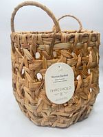 Front view of round woven basket showing handles and tag