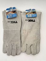Two pairs of grey welding gloves side by side showing full gloves and brand print
