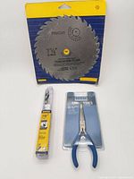 All three packaged items: saw blade, pliers, drill bit