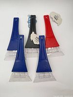 Group of five ice scrapers—three blue, one red, one black—showing front view