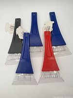 Five ice scrapers laid out showing front view, tags attached