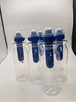 Group of six identical clear bottles with blue filters visible