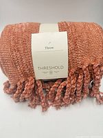 Folded coral throw blanket with label