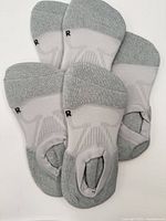 Top view of multiple grey low-cut compression socks showing right-foot marking and mesh pattern