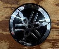 Front view of Yamaha emblem showing tuning-fork logo and wear