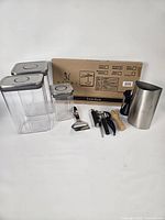 Group shot of three OXO canisters, boxed pasta rack, stainless pitcher and assorted utensils